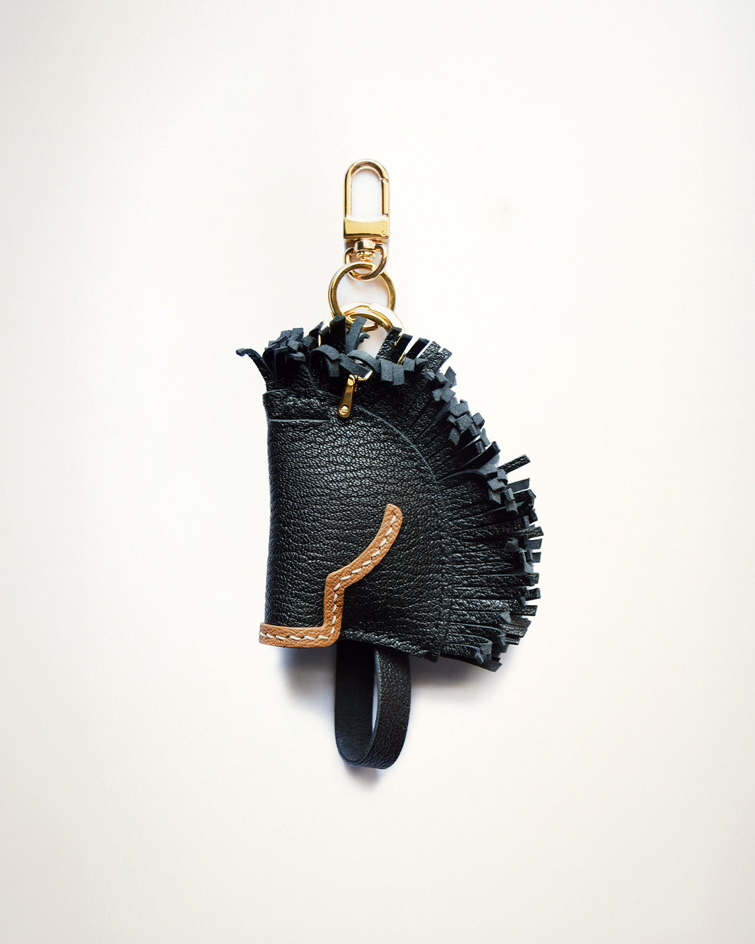 Mochi Manner handmade full-grain sheep leather black stallion charm with fringe details, tan trim, and gold-plated hardware

