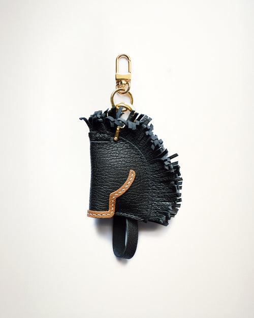 Mochi Manner handmade full-grain sheep leather black stallion charm with fringe details, tan trim, and gold-plated hardware

